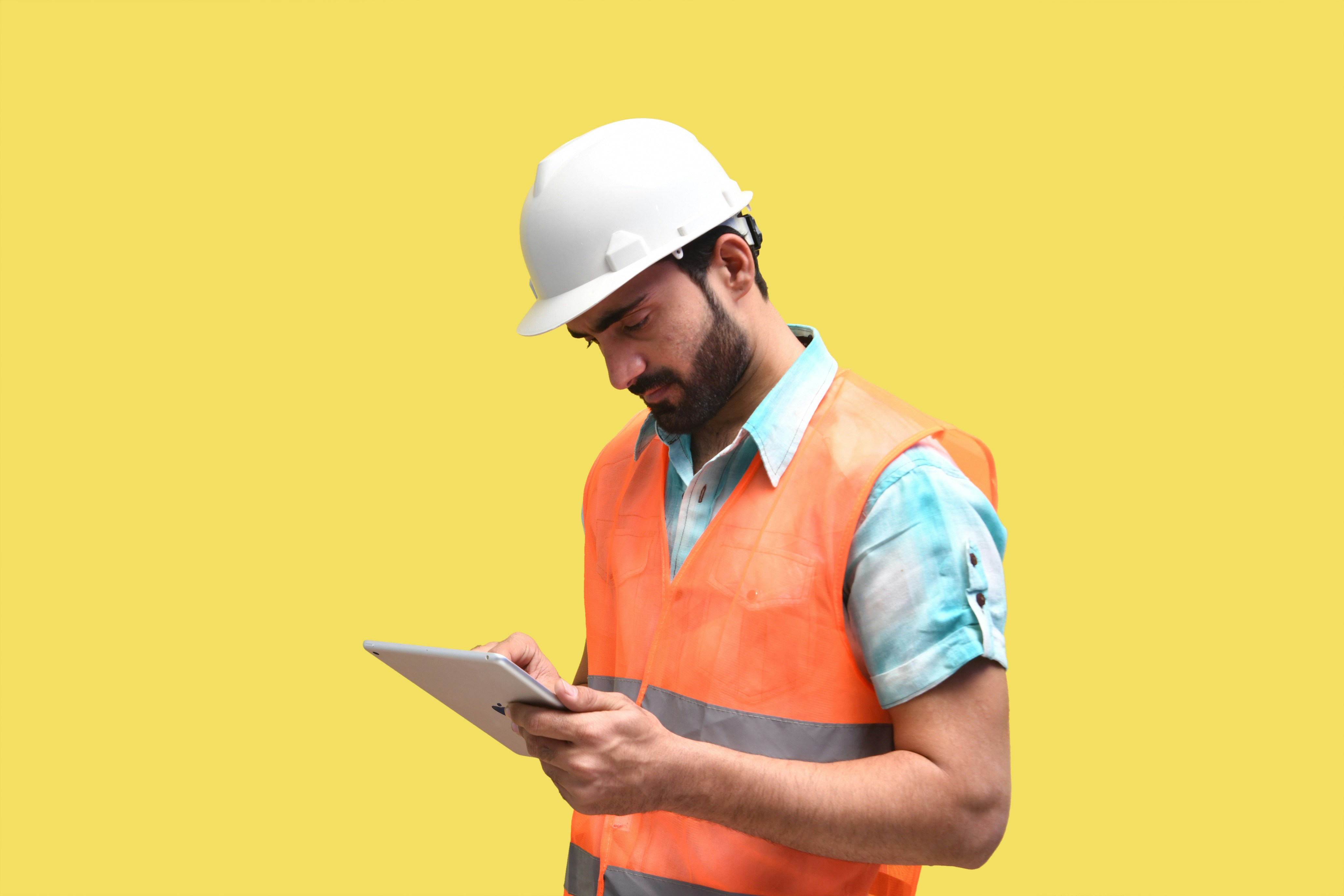 Inspector in a hard hat reviewing a tablet on a factory floor
